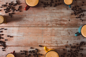 Colorful coffee cups with coffee beans on vintage wooden surface. Copy space. Selective focus.