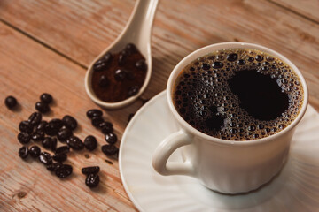 Coffee cup with coffee beans on vintage wooden surface. Copy space. Selective focus.
