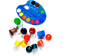 Jars with gouache multicolored paint, palette, brush. Top view.Flat lay