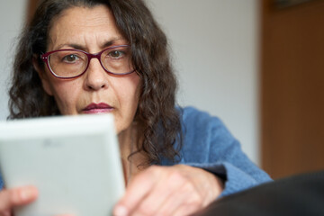 Close up of senior woman with glasses reading ebook