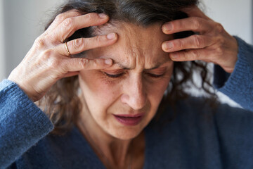 Fototapeta premium Mature woman with strong migraine holds head with ands