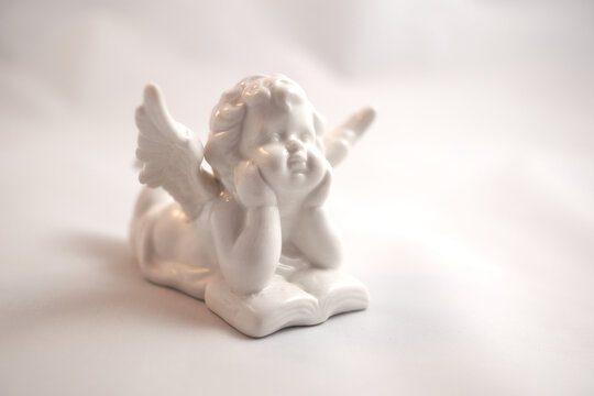 Porcelain angel with a book on a white surface
