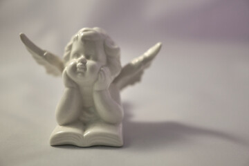Porcelain angel with a book on a white surface