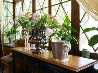 A beautiful bouquet of peonies in daylight on a wooden windowsill. Wilted pink peonies in a vase on the background of the window. High quality photo