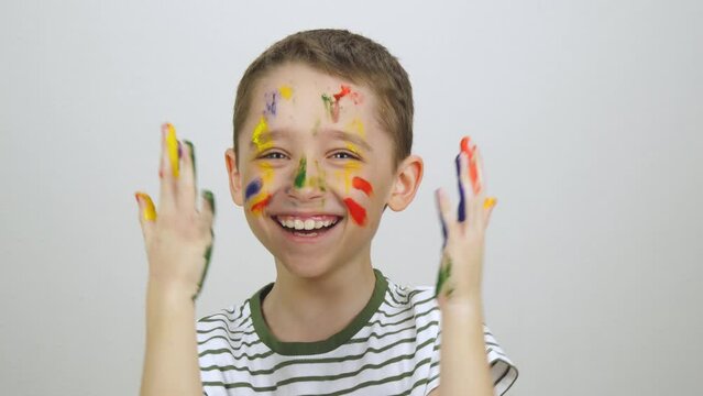 A cheerful boy touches his face with his hands while playing hide-and-seek. The face of a happy child in bright colors. Children's games, happy childhood and creativity