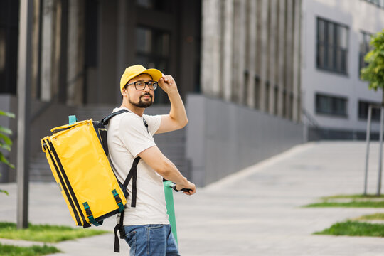 Man courier on scooter in town streets with a hot food delivery from takeaways and restaurants to home, express food delivery and shopping online concept. Delivery food by scooter.