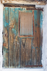 Old wooden door, discolored and with a ventilation grill
