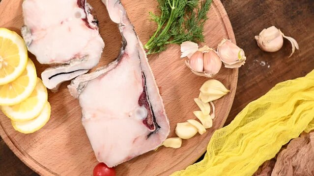 Raw fish cod on a tray, lemon tomato and pepper, wooden table in rustic style rotation. High quality 4k footage