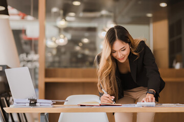 Asian businesswoman in formal suit in office happy and cheerful during using smartphone and working