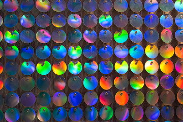Glitter background, abstract, shiny circles wall multi-colored bright twinkles and shadows. Glowing metal shimmering fabric texture close up. Sparkling sequined textile. Event decoration on photo zone