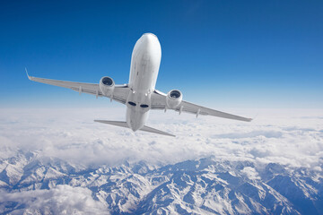 Aerial view mountains from airplane. Flying over snow mountain valley in pure sunshine with clouds passing by.