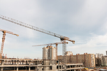 Construction cranes at a construction site in the city against the blue sky. The concept of building a new area. Construction of a new building.
