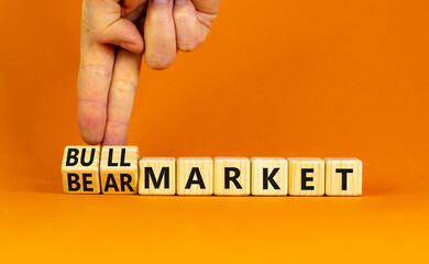 Bull or bear market symbol. Businessman turns wooden cubes and changes words Bear market to Bull market. Beautiful orange table orange background, copy space. Business bull or bear market concept.