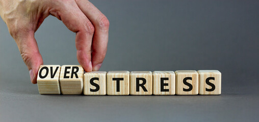 Over stress symbol. Psychologist turns wooden cubes and changes the concept word Stress to Over stress. Beautiful grey table grey background, copy space. Psychlogical over stress concept.