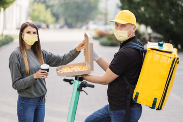 Pizza Delivery. Caucasian courier deliveryman in yellow uniform and face mask giving woman food...