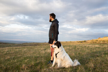 Obraz premium man and his white dog on a hill