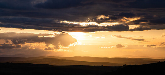 amazing sunset sky over green hills in early summer