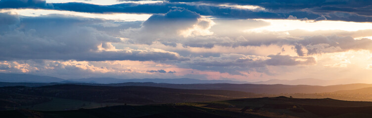amazing sunset sky over green hills in early summer