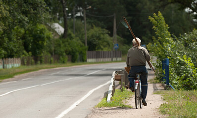 a man with a scythe rides a bicycle to mow the grass