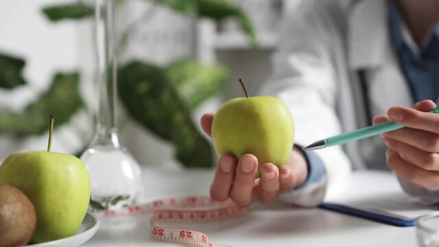 Doctor explains the usefulness and benefits of the apple fruit. Patient the appointment with a nutritionist. Doctor's advice on proper nutrition. Healthy food for your body. Hand holding a green apple