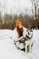 Happy young woman winter clothes walking the dog in the snow winter holidays