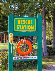 Safety equipment, lifebuoy or rescue buoy hanging on the board. Red lifebuoy on a wooden surface by the lake