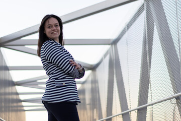 Obraz premium close-up view of a smiling businesswoman with her arms crossed looking at the camera on the street at sunset. Successful business