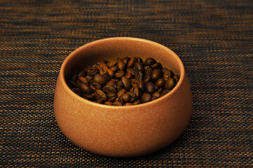 Coffee beans in a cup on a table in dark lighting. Shallow depth of field