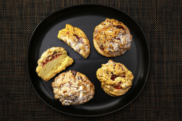Cookies with raspberry jam on a black plate under dark lighting. View from above