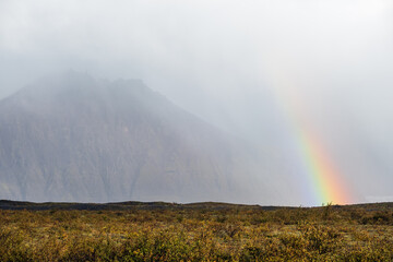 Mountain and rainbow view during auto trip in Iceland. Spectacular rain weather Icelandic landscape with scenic nature.