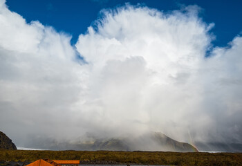 Mountain and rainbow view during auto trip in Iceland. Spectacular rain weather Icelandic landscape with scenic nature.
