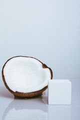 Halved coconut on white background with reflection and props for product.