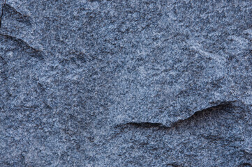 Texture of an old gray wall of granite stones with cracks and spots close-up