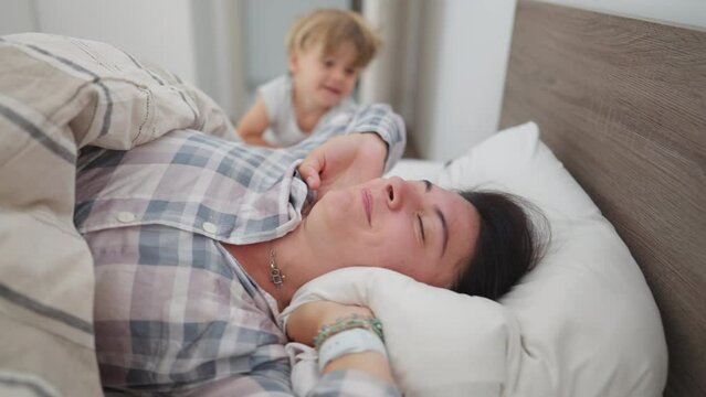 Woman getting up from bed rubbing face and starting the day