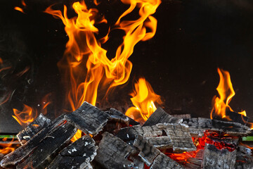 Bright orange flashes of fire from a bonfire on coals