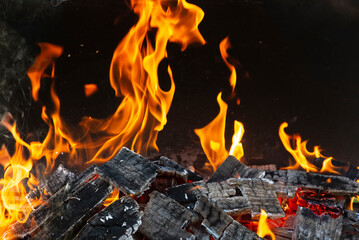 Bright orange flashes of fire from a bonfire on coals