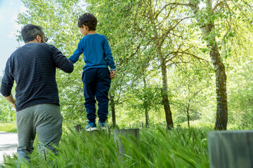 father helping his son balance on a wooden pole. father's day concept