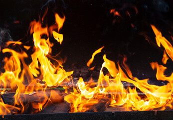 Bright orange flashes of fire from a bonfire on coals