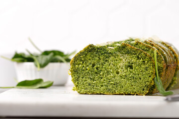 Spinach cake with Flaked almonds cutted on marble board. Pieces of Sponge green pie. Grey background. Green cake texture