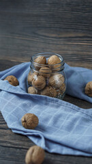 walnuts in a jar close-up on a wooden background. around the jar is a blue kitchen towel