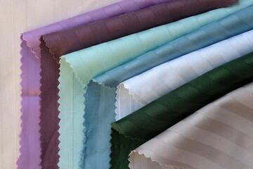 Samples of color stripe satin background. Beautiful high-quality fabric for sewing bed linen. Cotton textiles of white, green, burgundy color top view. Bed linen fabric samples.