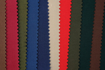 Colourful samples of fabric for sewing bags and backpacks. polyester blue, green, beige and red fabric. Palette of samples of a dense fabric of different shades.