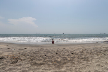 A lonely Woman watching caribbean sea landscape and a ships far away in sunny airport Santa Marta beach