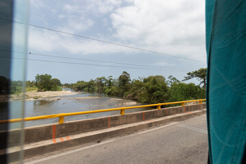Colombian Palomino River viewed from a bus window at sun route highway in sunny day