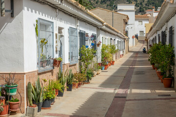 Typical street of an Andalusian town with low white houses adorned with many flowerpots