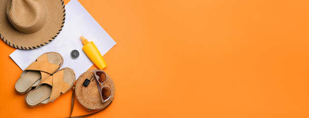 Beach accessories, world map, compass and bottle of sunscreen on orange background with space for text