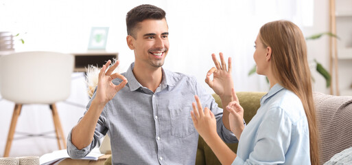 Obraz premium Young deaf mute couple using sign language at home