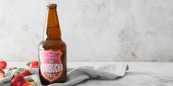 Bottle of fresh strawberry kombucha on grunge background with space for text