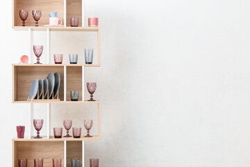 Wooden shelf unit with stylish empty glasses on white background