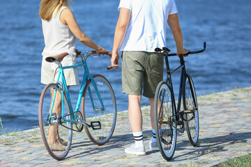 Mature couple with bicycles walking along river bank on summer day